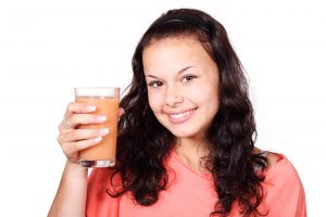 Beautiful smiling girl holding a glass of juice