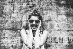Smiling woman with sunglasses clicking picture